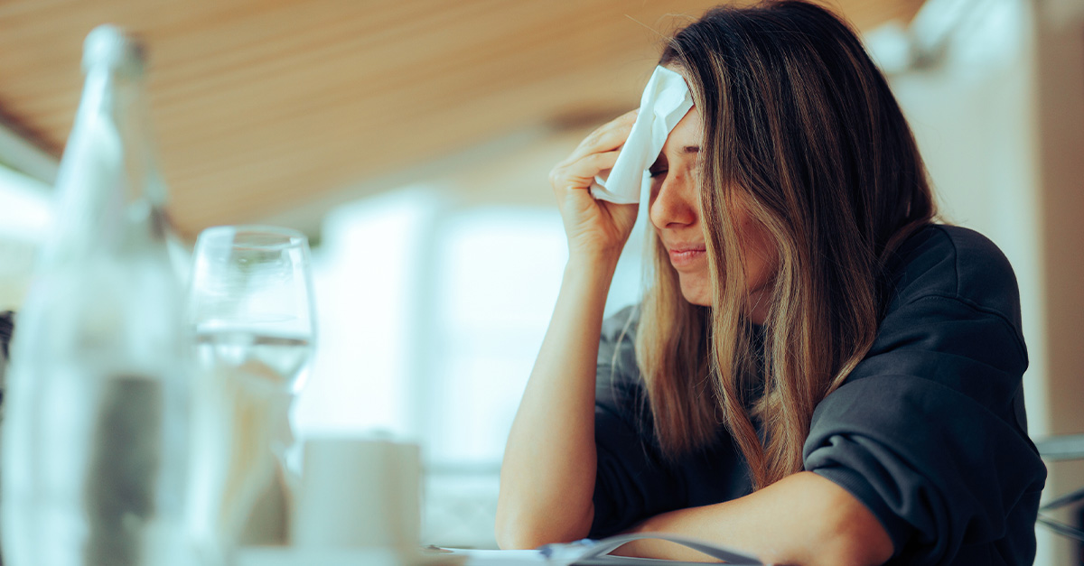 A lady dealing with hot flashes due to menopause in the summer heat.