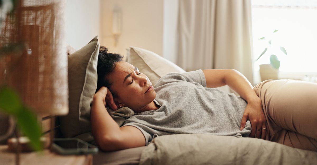 Woman lying on bed holding her abdomen